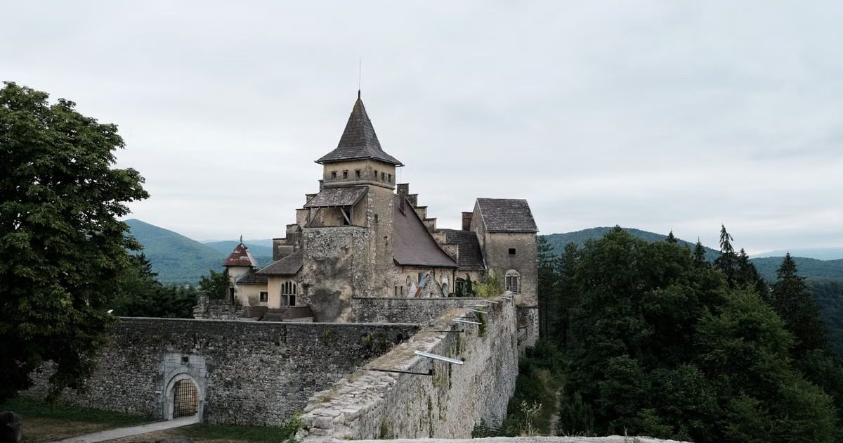 Explore the medieval Ostrozac Castle, nestled among lush hills, with its fortified walls and towers.