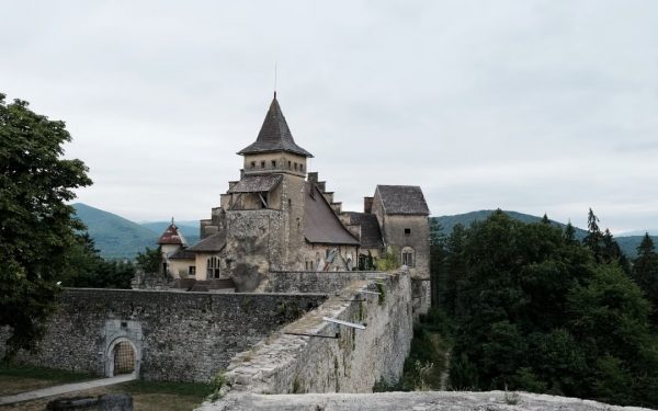 Explore the medieval Ostrozac Castle, nestled among lush hills, with its fortified walls and towers.